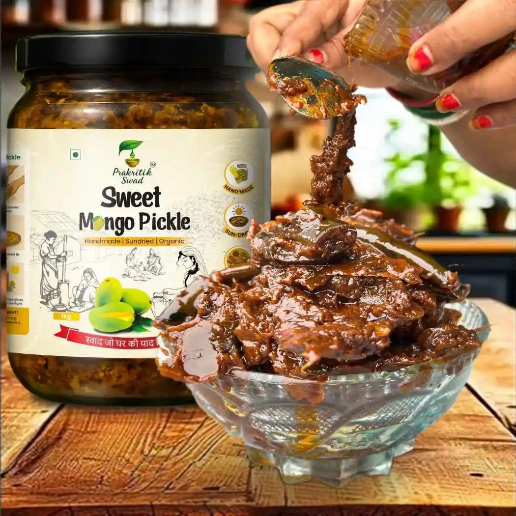 Sweet Mango Pickle jar with a spoonful of pickle being poured into a glass bowl on a wooden surface.