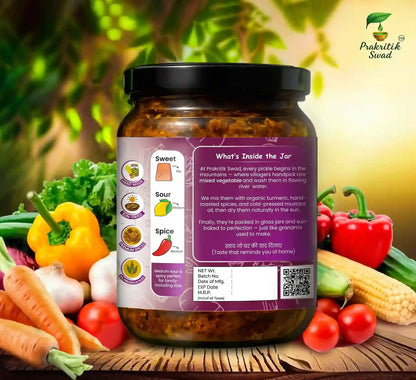 Jar of pickles with a label on a wooden surface surrounded by vegetables, featuring the brand 'Prakritik Swad'.